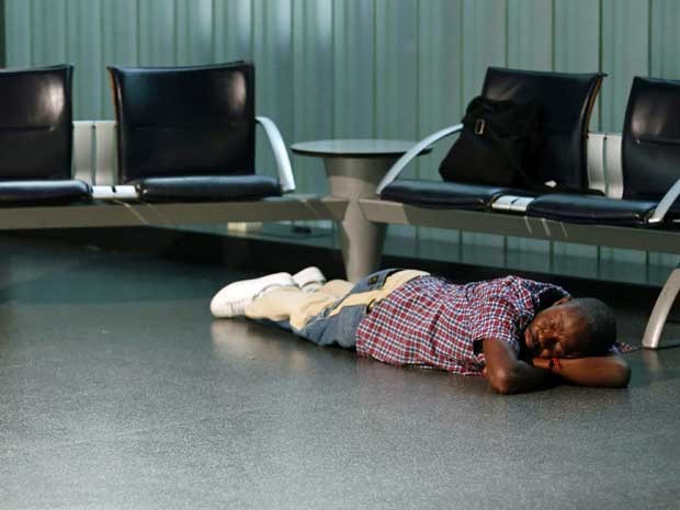 Passageiro dorme no terminal da Lufthansa no Aeroporto Fraport, em Frankfurt. (Foto: Kai Pfaffenbach / Reuters)
