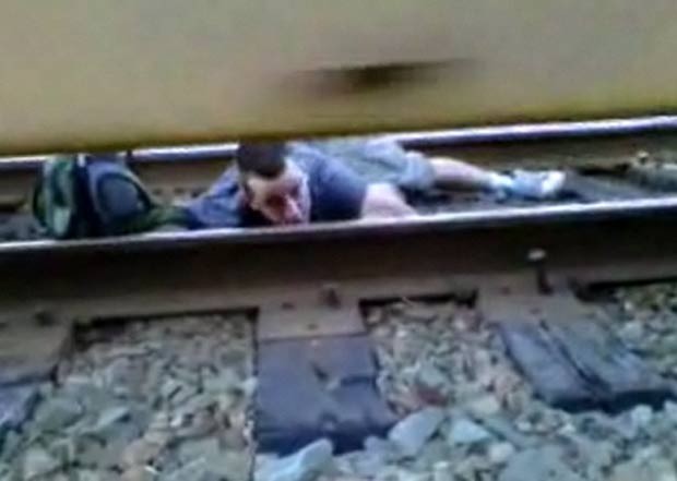 Jovem se arriscou ao ficar deitado sobre os trilhos enquanto trem passava. (Foto: Reprodução)