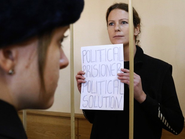 A brasileira Ana Paula Maciel, integrante do Greenpeace, segura cartaz com os dizeres 'Presa política, solução política', no tribunal em São Petersburgo, Rússia, onde está presa desde 19 de setembro. (Foto: Dmitry Lovetsky/AP)