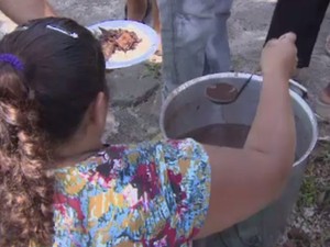 Assentada distribuindo feijão durante protesto em frente ao Incra, no Amapá (Foto: Reprodução/TV Amapá)