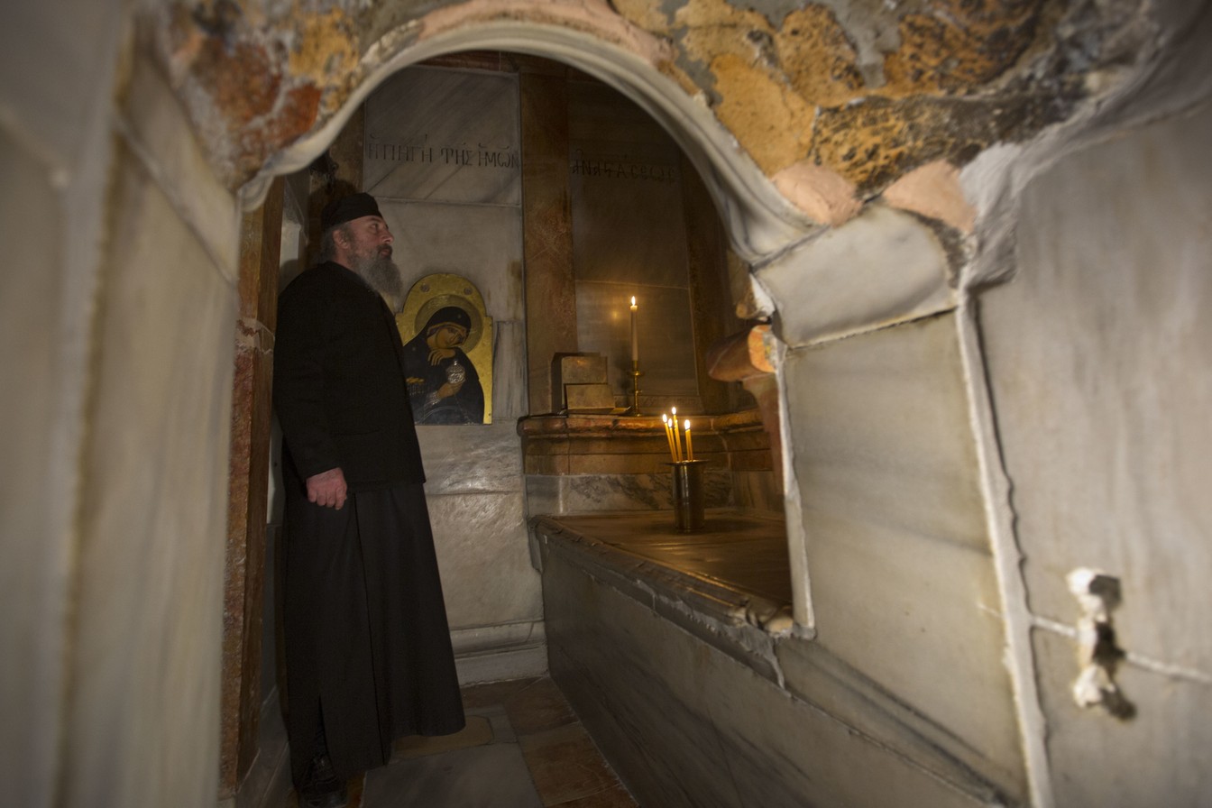 Um padre da Ingreja Ortodoxa Grega dentro da edícula da Igreja do Santo Sepulcro, em Jerusaleém (Foto: Sebastian Scheiner/AP)