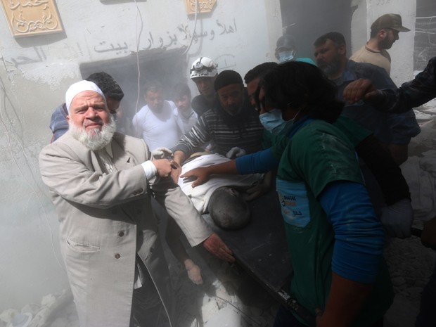 Civis e membros de uma equipe de resgate retiram o corpo de um homem de um edifcio atingido por bombas lanadas por foras do governo em Aleppo, na Sria, na quarta (29) (Foto: AFP Photo/AMC/Zein Al-Rifai)