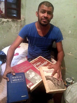 Cícero Pereira Batista, de 33 anos, mostra livros achados no lixo e com os quais estudou para virar médico (Foto: Raquel Morais/G1)