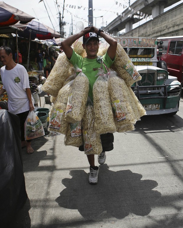 Vendedor foi visto carregando diversos pacotes de macarrão em mercado de Manila, nas Filipinas (Foto: Aaron Favila/AP)