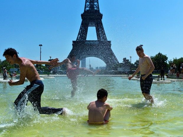 Garotos brincam na fonte dos jardins do Trocadero, em frente à Torre Eiffel, em Paris (Foto: Thibault Camus/AP)
