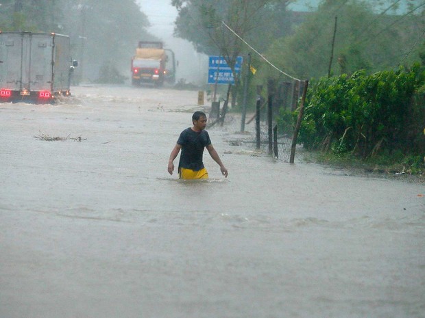 Um homem atravessa região inundada nas Filipinas (Foto: Bullit Marquez / AP Photo)