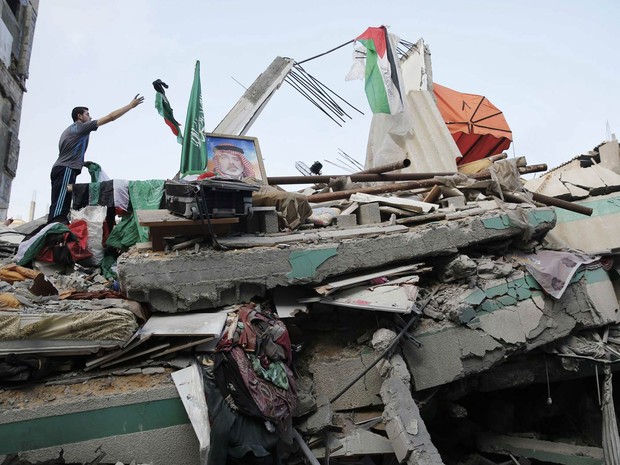 29/7 - Palestino joga uma bandeira sobre os destroços da casa de Ismail Haniyeh, um dos líderes do Hamas, atingida por míssil israelense antes do amanhecer desta terça-feira (29) na Cidade de Gaza (Foto: Finbarr O'Reilly/Reuters)