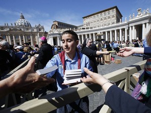 Voluntários distribuem evangelho de bolso na praça de São Pedro (Foto: Tony Gentile/Reuters)