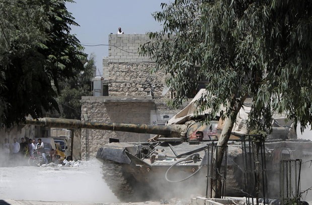 Rebeldes capturam tanque das tropas oficiais sírias, observados por civis, em bairro de Aleppo neste sábado (4) (Foto: Ahmad Gharabli/AFP)