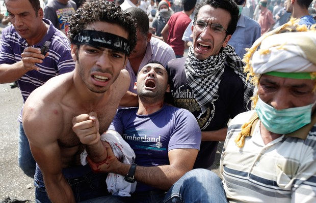 Manifestante ferido é socorrido por colegas após confrontos com as forças de segurança nos arredores da Praça Ramses, no Cairo (Foto: AP Photo/Hassan Ammar)