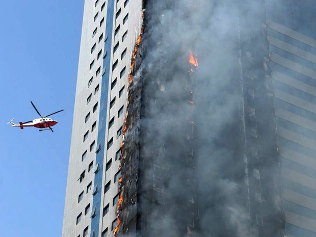 Helicóptero sobrevoa prédio em chamas em Sharjah, nos Emirados Árabes Unidos, na quinta (1º) (Foto: AP Photo)