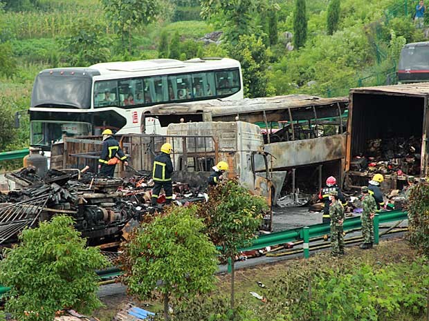 Bombeiros ainda trabalham no resgate de corpos e no rescaldo após colisão seguida de explosão em estrada na China. (Foto: AFP Photo)