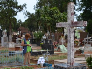 Cicera Quitéria, de 69 anos, acende vela na sepultura do esposo no cemitério Santo Antônio, em Campo Grande (Foto: Anderson Viegas/G1 MS)