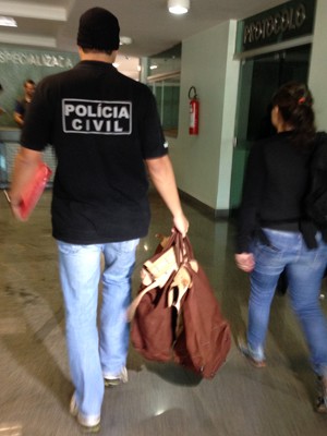 Policial do DF carrega sacola com itens apreendidos na casa dos suspeitos de integrar facção criminosa (Foto: Natalia Godoy/G1)