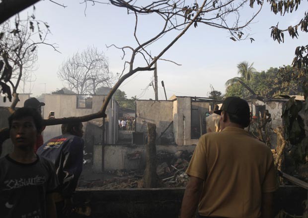 Destroços de casas incendiadas pela queda do avião (Foto: AFP)