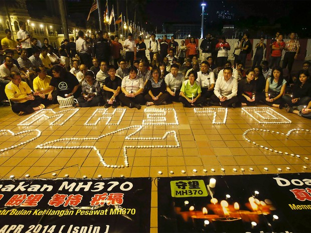 Familiares dos passageiros do voo da Malaysian Airlines acendem velas em vigília para marcar um mês do desaparecimento do avião (Foto: Reuters/Samsul Said )