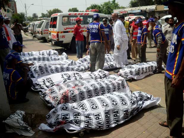 Voluntários ao lado de vítimas da explosão de uma bomba em Karachi. (Foto: Rizwan Tabassum / AFP Photo)