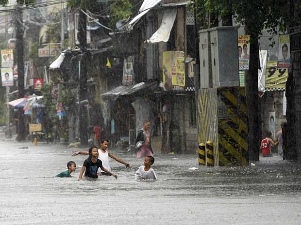 Crianças brincam em rua inundada em Manila. (Foto: Bullit Marquez / AP Photo)