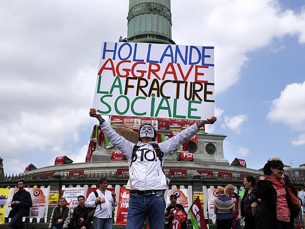 Manifestante mascarado segura cartaz com a frase "Hollande agrava as divisões sociais", durante protesto em Paris neste domingo (5) contra as medidas austeras do presidente francês, François Hollande (Foto: Thomas Coex/AFP)