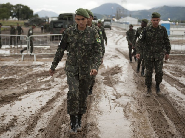 Soldados caminham na lama no Campo da fé em Guaratiba (Foto: Nicolas Tanner/AP)