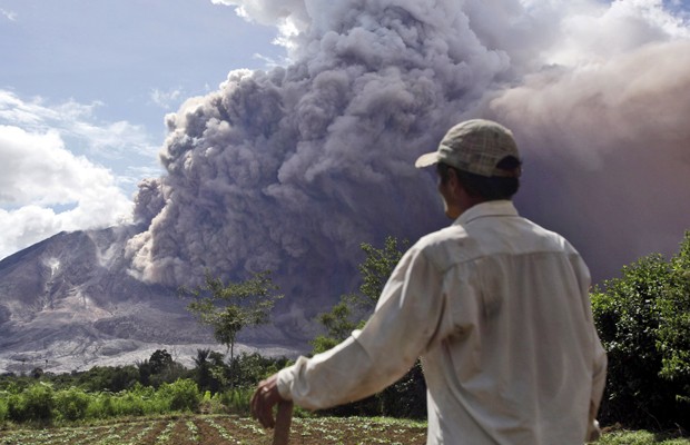 Fazendeiro observa a fumaça saindo do monte Sinabung em Tiga Pancur, na Indonésia, neste sábado (13) (Foto: Binsar Bakkara/AP)
