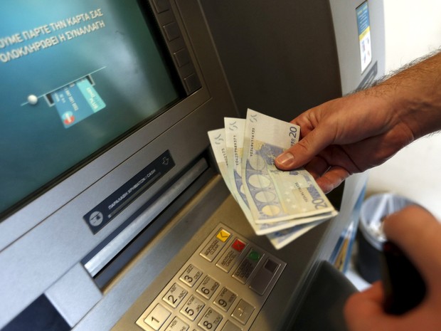Um homem saca 60 euros, o limite máximo diário, em um caixa eletrônico em Piraeus, perto de Atenas, na Grécia. Nesta terça (30) termina o prazo para que o país pague uma parcela de 1,6 bilhão de euros ao FMI e continue na Zona do euro (Foto: Yannis Behrakis/Reuters) Um homem saca 60 euros, o limite máximo diário, em um caixa eletrônico em Piraeus, perto de Atenas, na Grécia. Nesta terça (30) termina o prazo para que o país pague uma parcela de 1,6 bilhão de euros ao FMI e continue na Zona do euro (Foto: Yannis Behrakis/Reuters)
