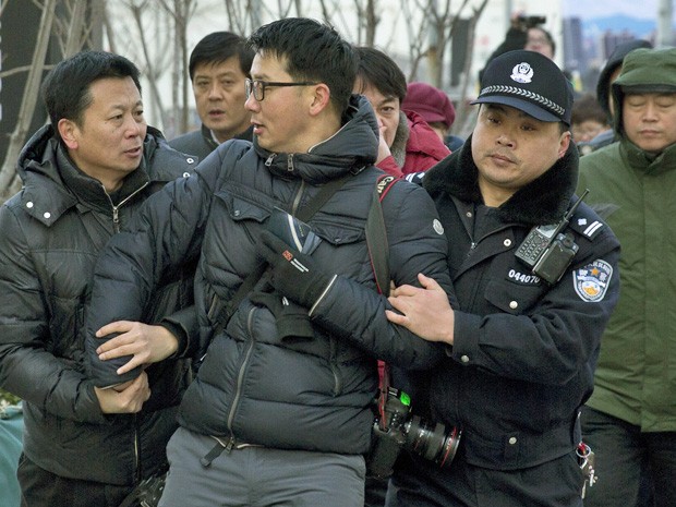 Policiais chineses prendem fotógrafo que trabalhava próximo a tribunal onde foi lido o veredito de Xu Zhiyong. (Foto: Andy Wong/AP)