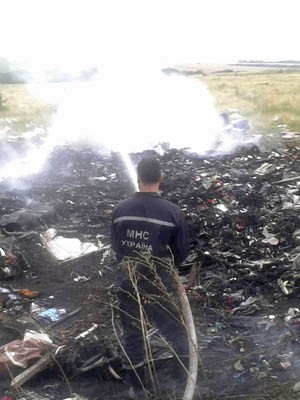 Homem apaga incêndio no local da queda do avião Malaysia Airlines Boeing 777 na região de Donetsk (Foto: Maxim Zmeyev/Reuters)