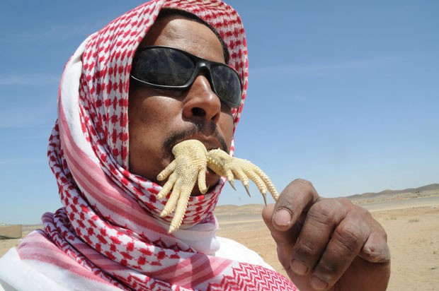 Homem devora lagarto em deserto na Arábia Saudita (Foto: Mohamed Al Hwaity/Reuters)