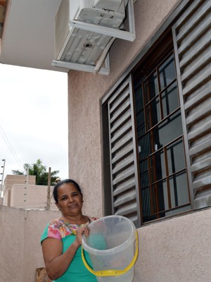 Dona de casa Rosilene Matos de Souza recolhe água condensada pelo ar-condicionado para lavar a varanda e o quintal (Foto: Anderson Viegas/Do G1 MS)