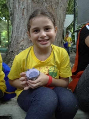 Maria Luísa, com o bolinho de hipopótamo, fez muitos amigos na colônia de férias (Foto: Moema França/G1)