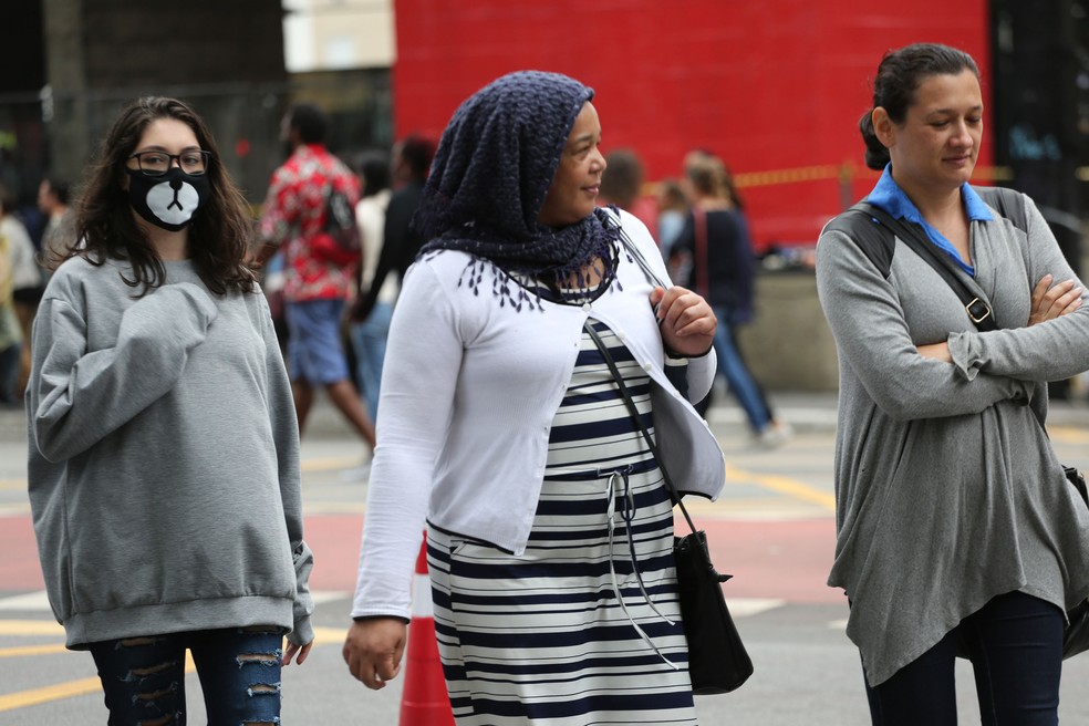 Pedestres se protegem do frio na Avenida Paulista, em São Paulo, na tarde deste domingo (19), último dia do verão.  (Foto: Renato S. Cerqueira/Futura Press/Estadão Conteúdo)