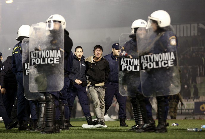 Torcedor do Panathinaikos levado preso e sangrando pela polícia (Foto: AP Photo/Yorgos Karahalis)