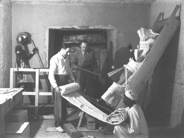 Howard Carter trabalhando com seu amigo e colega Arthur Callender para embrulhar uma das duas estátuas do rei, fotografia colorizada (Foto: Reprodução/GriffithInstitute)
