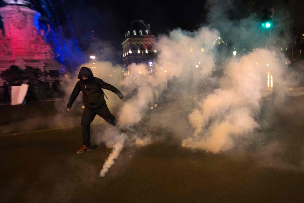 Manifestante foge de gás lacrimogêneo durante protesto contra resultado do segundo turno da eleição presidencial em Paris  (Foto: Emilio Morenatti/AP)