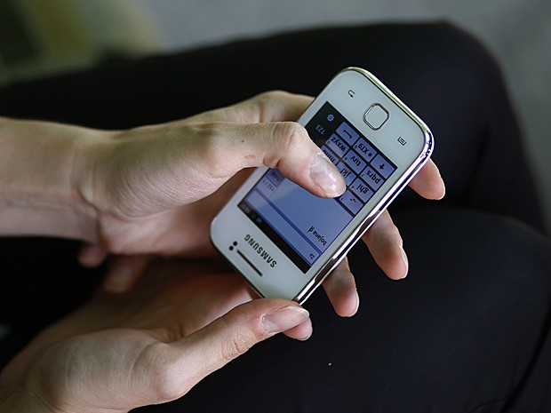 Para poder mandar SMS, Bojana precisa inverter a posição do celular (Foto: Marko Djurica/Reuters)