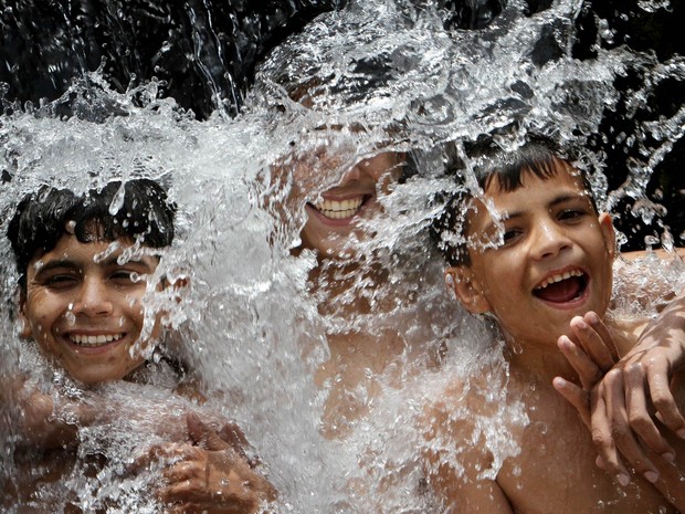 Meninos paquistaneses se refrescam e brincam tomando banho juntos durante dia quente em Karachi. A onda de calor no país levou a temperaturas chegaram a 49°C (Foto: Fareed Khan/AP)