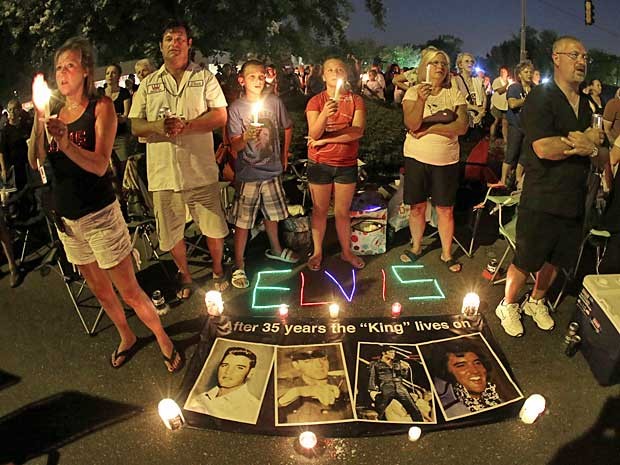 Com velas, flores e cartazes, fãs de Elvis Presley fazem vigília noturna em frente à mansão do cantor, em Graceland, no Tennessee, para lembrar os 35 anos de sua morte. (Foto: Mark Humphrey / AP Photo)