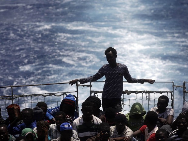 Imigrantes sentam no deque do navio belga Godetia após serem resgatados no Mar Mediterrâneo na costa da Líbia. Os Médicos Sem Fronteiras pediram que a UE melhore urgentemente as condições dos centros de recepção dos imigrantes na Itália e Grécia (Foto: Gregorio Borgia/AP)