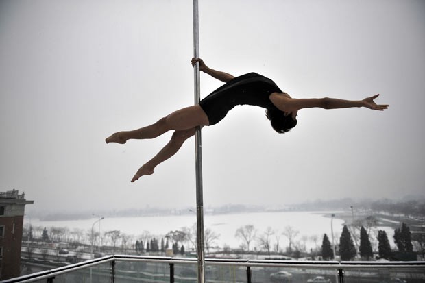 Chinesa faz performance de pole dance em meio à neve nesta quarta-feira (18) (Foto: AFP)