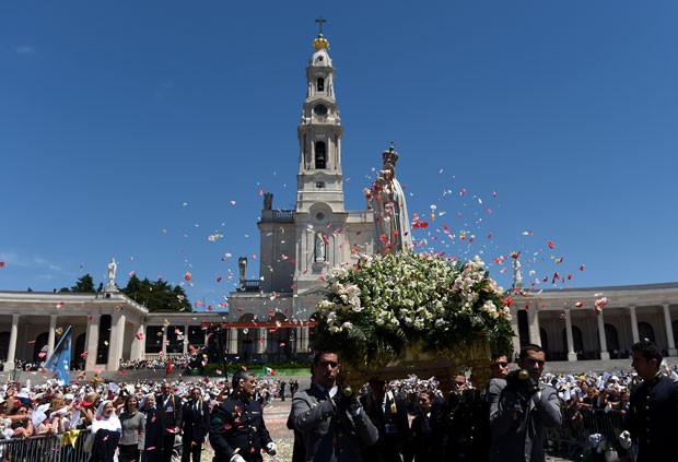 Imagem de Nossa Senhora de Fátima é carregada entre peregrinos em Portugal (Foto: Francisco Leong/AFP)