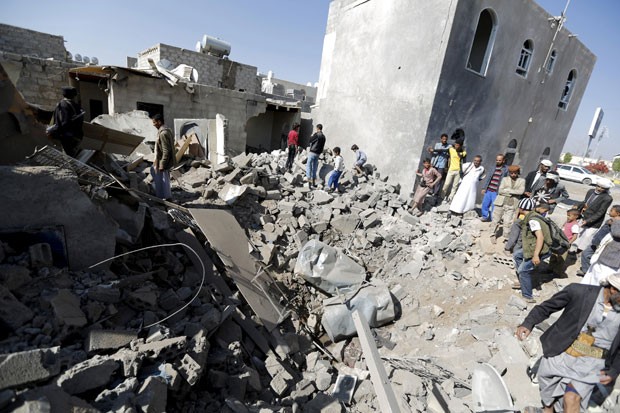 Pessoas são vistas nos destroços de casas que foram atingidas por um bombardeio perto do aeroporto de Sanaa nesta terça-feira (31) (Foto: Khaled Abdullah/Reuters)