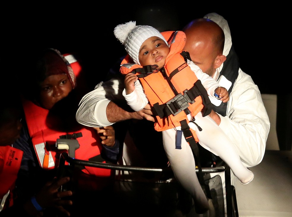 Membros da Guarda Costeira italiana seguram criança resgatada no Mediterrâneo por ONG  (Foto: REUTERS/Stefano Rellandini )