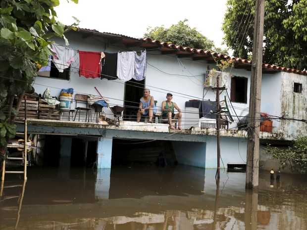 Família busca abrigo no topo de casa inundada em Assunção, Paraguai, neste domingo (27) (Foto: REUTERS/Jorge Adorno)