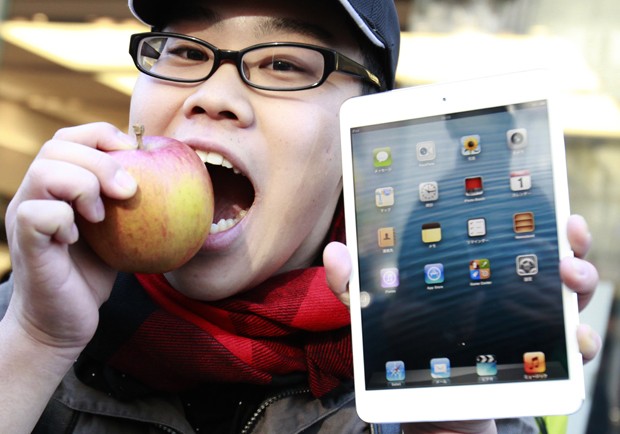 Fã Koudai Taguchi morde uma maçã enquanto mostra seu iPad mini recém comprado em uma loja de Tóquio (Foto: Yuriko Nakao/Reuters)