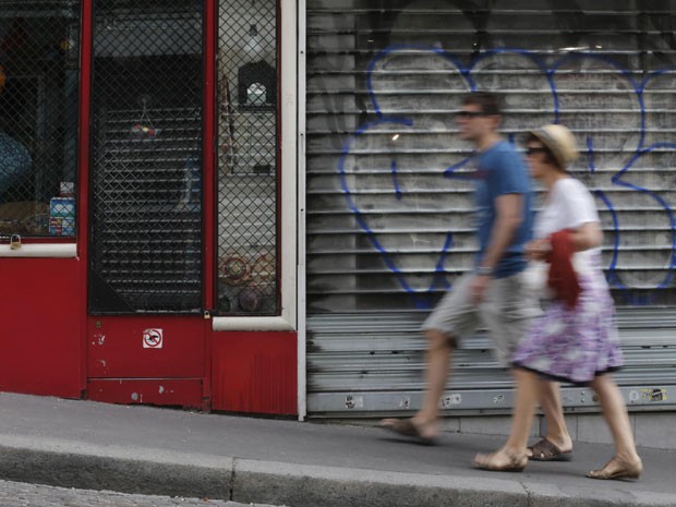 Turistas passam por lojas fechadas no bairro de Montmartre, em Paris (Foto: Christian Hartmann/Reuters)