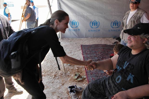 A atriz americana Angelina Jolie cumprimenta refugiado sírio nesta terça-feira (11) em campo na Jordânia (Foto: AFP)