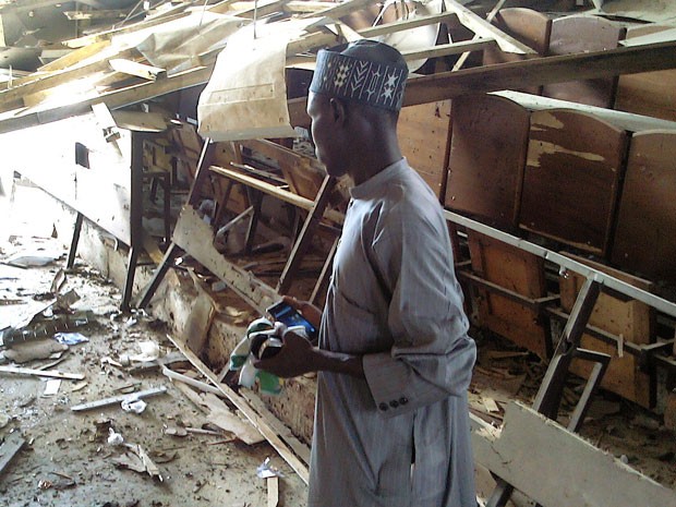 Estudante observa destruição causada em sala da Faculdade Federal de Educação, em Kano, na Nigéria, após ataque de atiradores na quarta-feira  (Foto: AFP Photo/Aminu Abubakar)