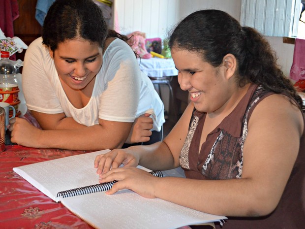 Katrinny é quem ajuda a irmã gêmea Kamilly na escola (Foto: Janine Brasil/G1)