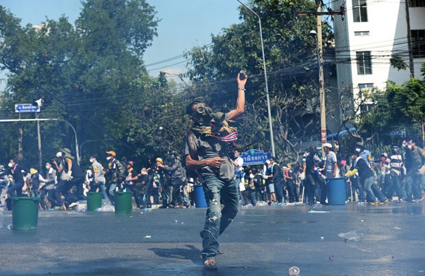  Manifestante joga pedra contra a polícia em protesto neste domingo (1º) em Bangcoc, na Tailândia. (Foto: Christophe ARCHAMBAULT/AFP)
